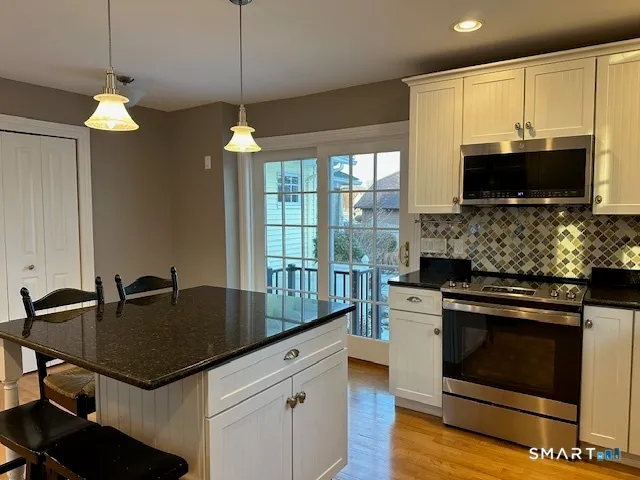 a kitchen with a stove a sink a microwave a dining table and chairs