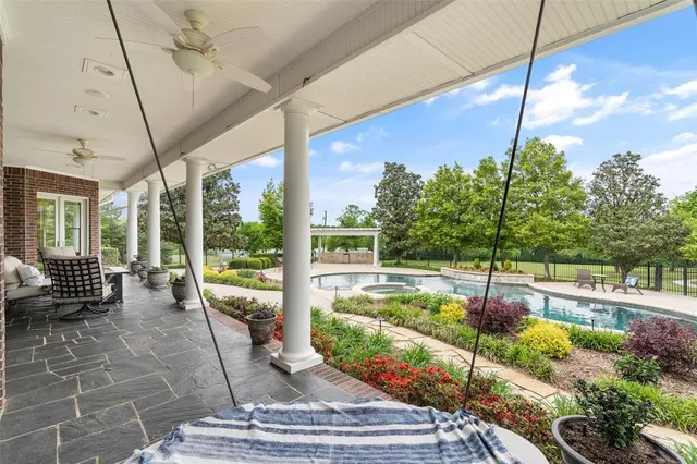 a view of a patio with couches plants and large trees