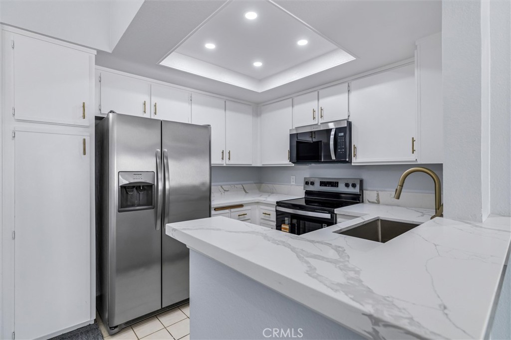 78 Costero Aisle, Unit 301 Irvine, CA 92614 - Photo 15 of 38 a kitchen with stainless steel appliances a refrigerator a stove a microwave a sink and a refrigerator