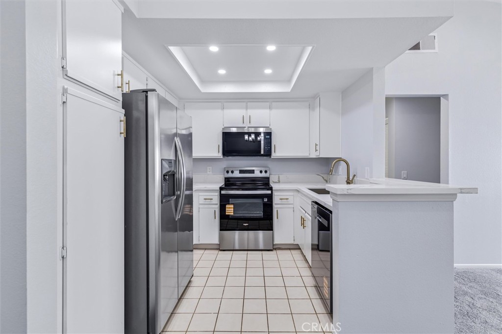 78 Costero Aisle, Unit 301 Irvine, CA 92614 - Photo 16 of 38 a kitchen with granite countertop a stove top oven and refrigerator