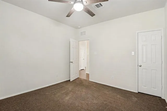 an empty room with chandelier fan and closet area