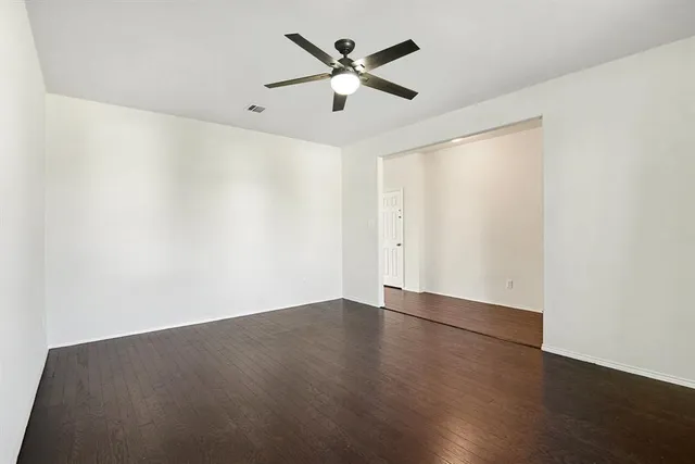 an empty room with wooden floor and ceiling fan