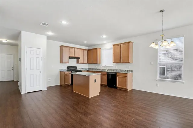 a open kitchen with kitchen island granite countertop wooden floors and white cabinets
