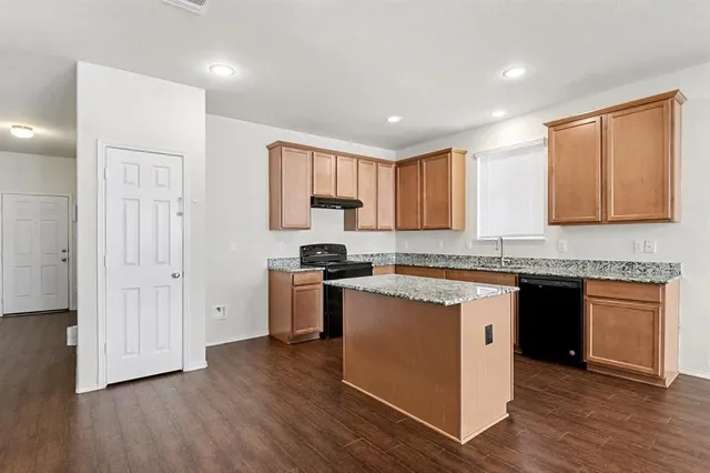 a kitchen with granite countertop wooden floors and white stainless steel appliances