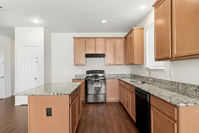 a kitchen with stainless steel appliances granite countertop a stove a sink and a refrigerator
