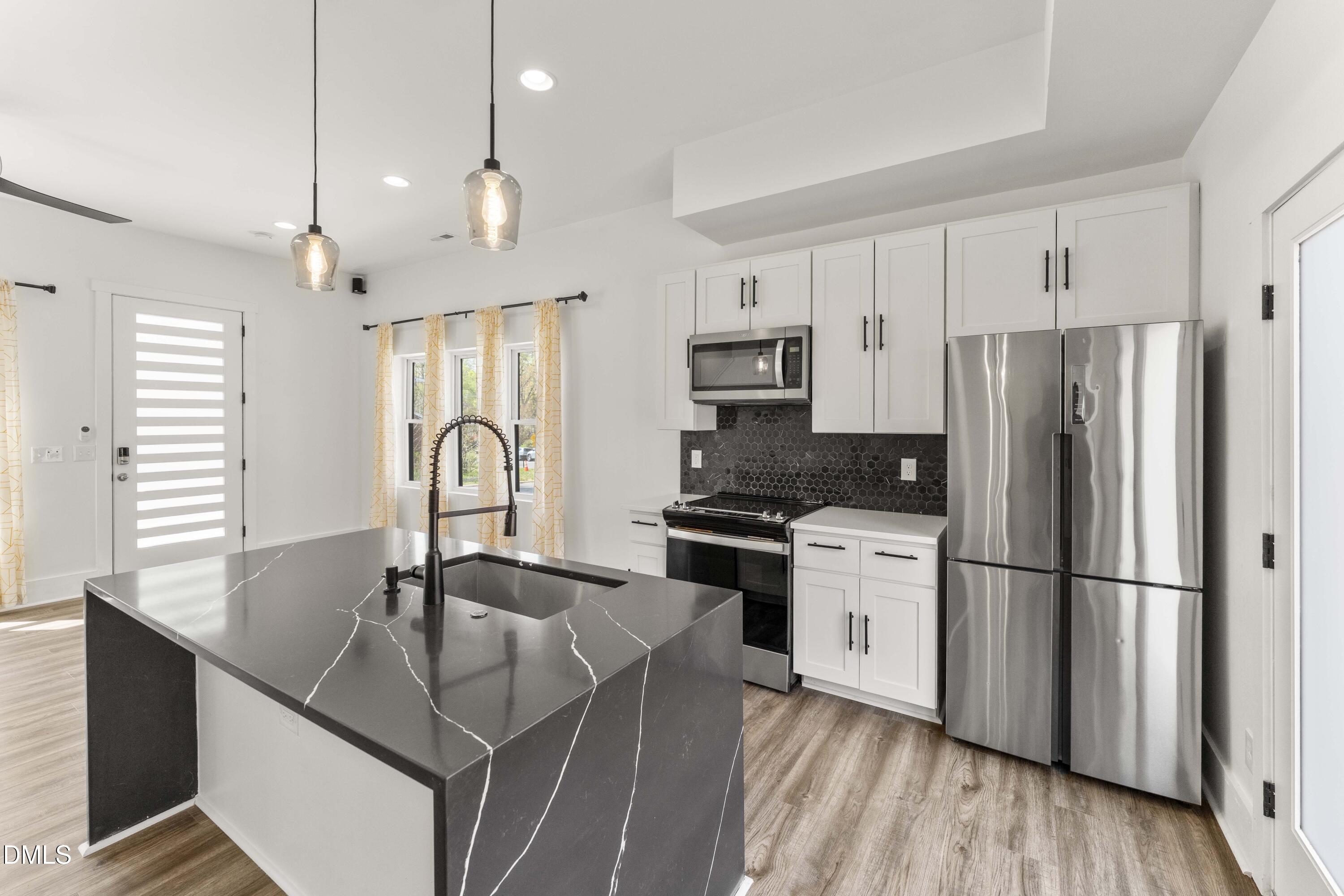 203 Nelson Street Durham, NC 27707 - Photo 3 of 29 a kitchen with kitchen island granite countertop a sink appliances a counter space and cabinets