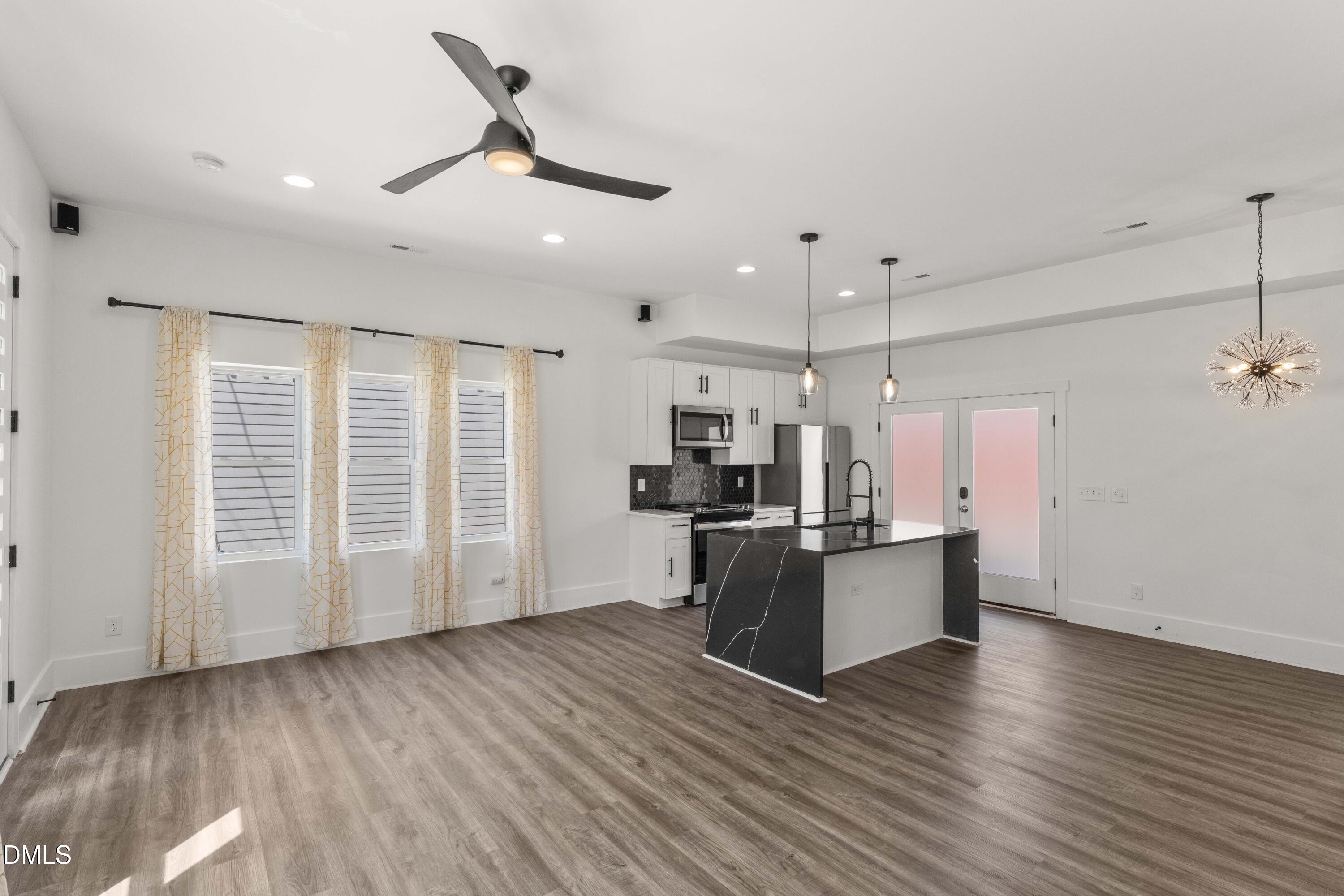 203 Nelson Street Durham, NC 27707 - Photo 7 of 29 a kitchen with stainless steel appliances kitchen island granite countertop a stove a refrigerator a sink a microwave oven with wooden floor and cabinets