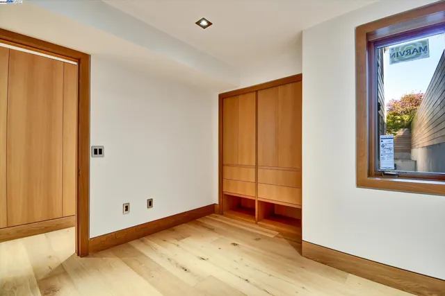 a view of a bedroom with wooden floor and windows