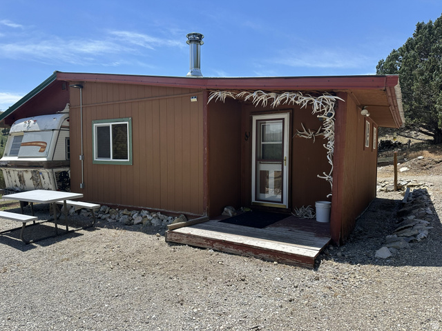 2006 Swenson Valley Road Bancroft, ID 83217 - Photo 37 of 51 Cabin exterior featuring horizontal wood siding, a metal chimney, and a covered entry porch