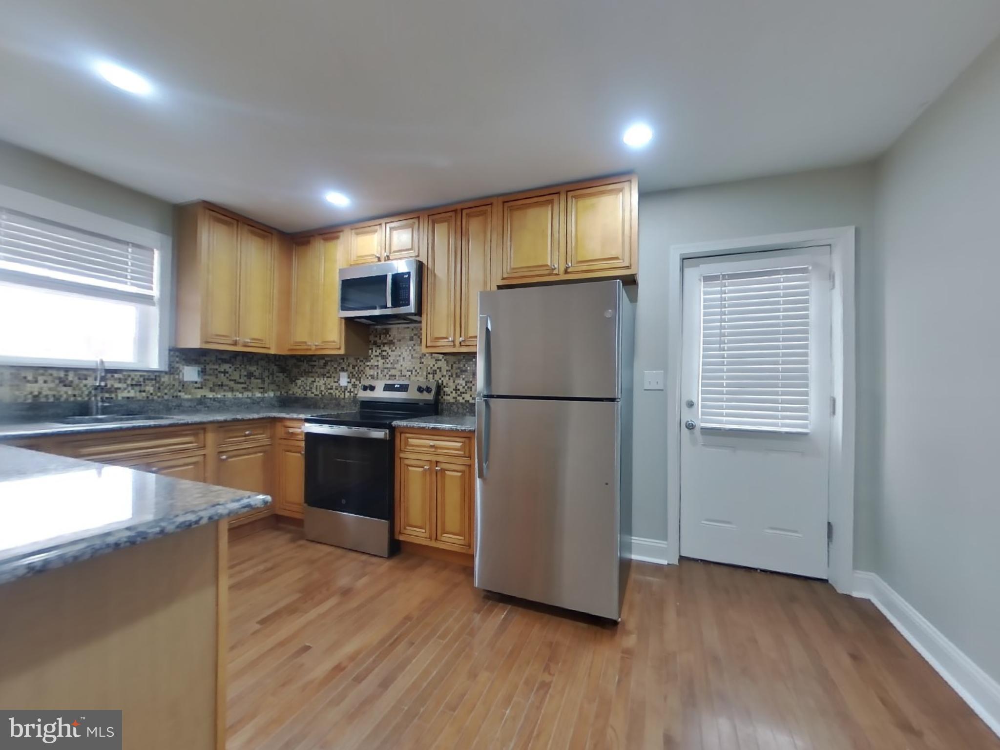 2000 Gaither Street Temple Hills, MD 20748 - Photo 5 of 21 a kitchen with granite countertop wooden floors stainless steel appliances and a window