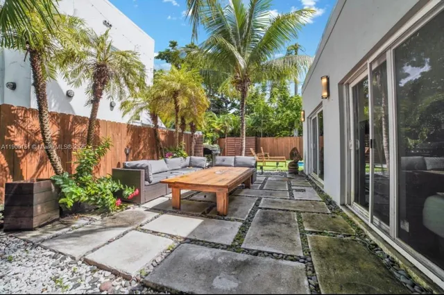 a backyard of a house with table and chairs potted plants