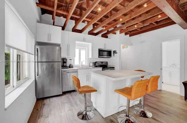 a living room with furniture a flat screen tv and kitchen view
