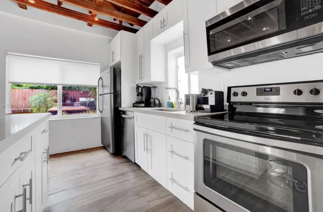 a kitchen with stainless steel appliances kitchen island granite countertop a stove a sink and white cabinets