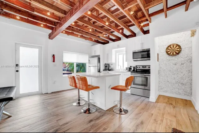 a view of a kitchen with kitchen island stainless steel appliances wooden floor and living room view