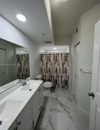 a bathroom with a double vanity sink toilet mirror and bathtub