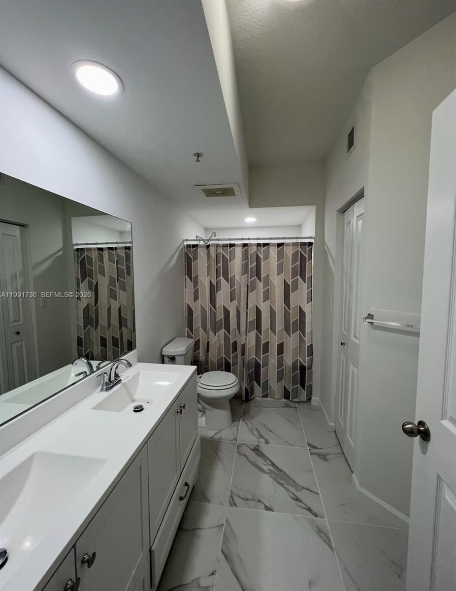 9172 Collins Avenue, Unit 214 Surfside, FL 33154 - Photo 16 of 33 a bathroom with a double vanity sink toilet and shower