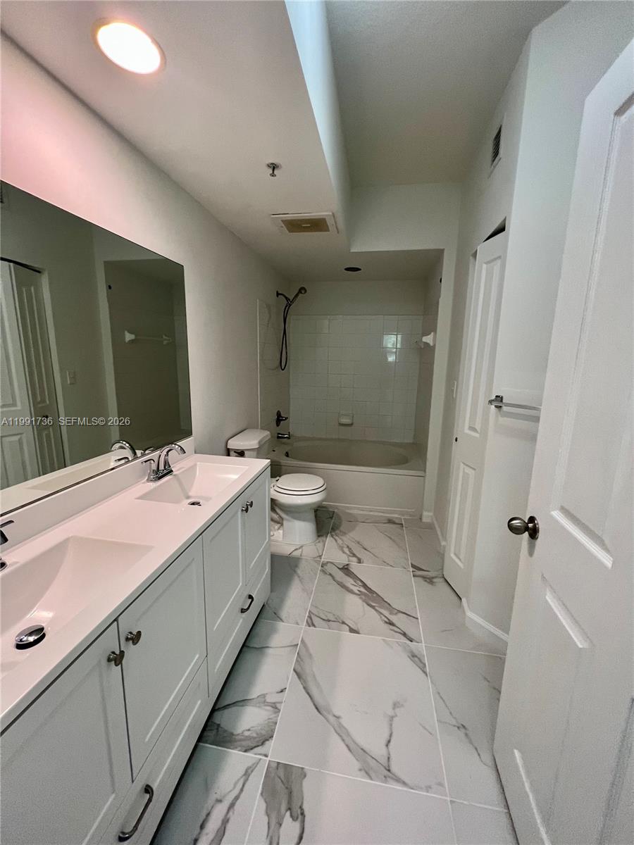 9172 Collins Avenue, Unit 214 Surfside, FL 33154 - Photo 18 of 33 a bathroom with a double vanity sink toilet mirror and bathtub