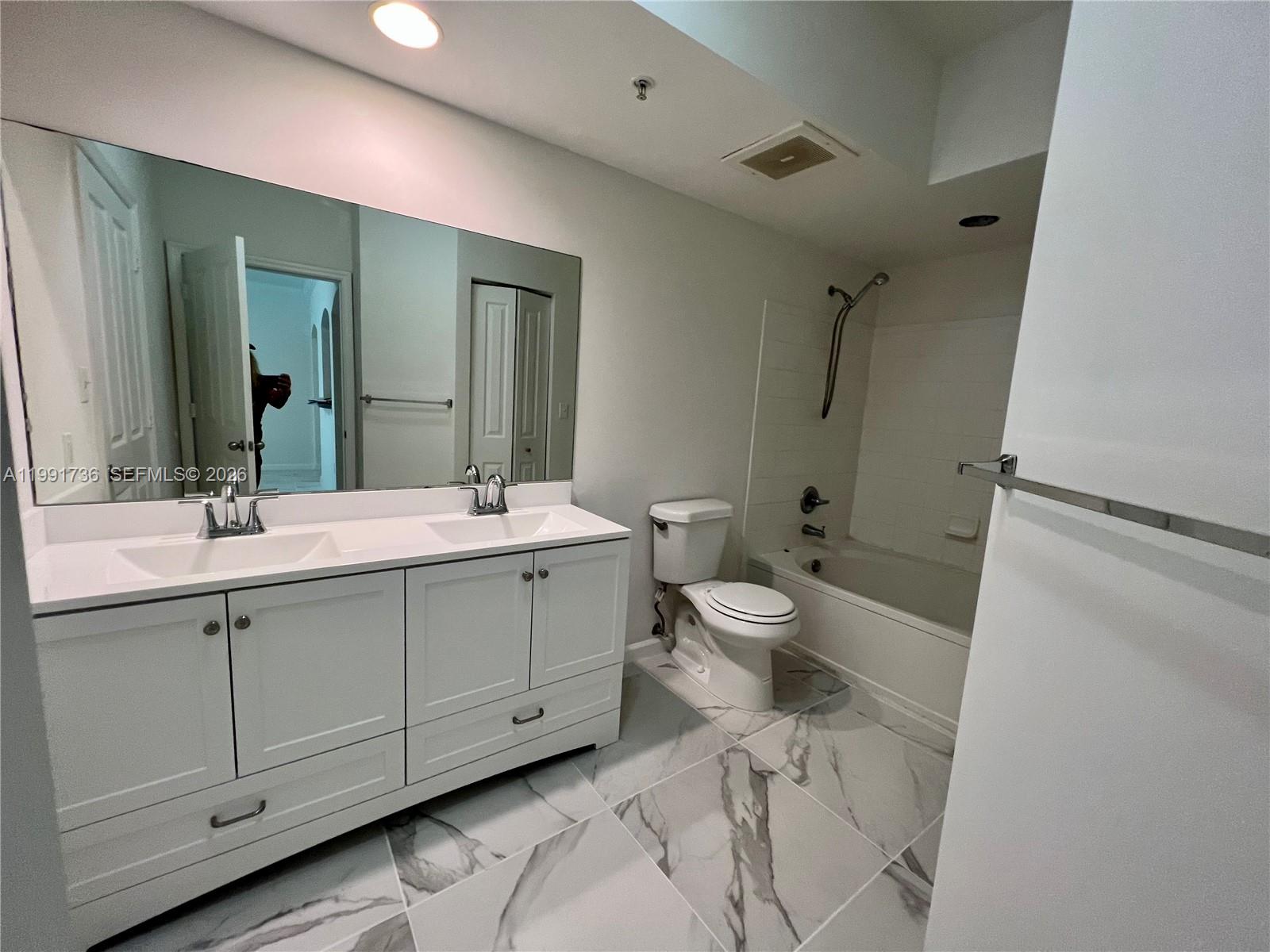 9172 Collins Avenue, Unit 214 Surfside, FL 33154 - Photo 19 of 33 a bathroom with a double vanity sink mirror and toilet