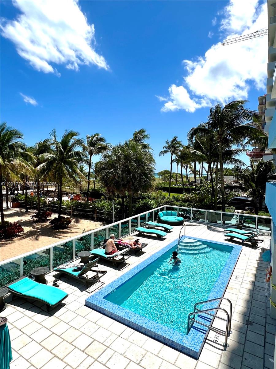 9172 Collins Avenue, Unit 214 Surfside, FL 33154 - Photo 27 of 33 a view of a swimming pool and lounge chairs