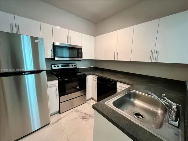 a kitchen with stainless steel appliances granite countertop a refrigerator and a stove top oven