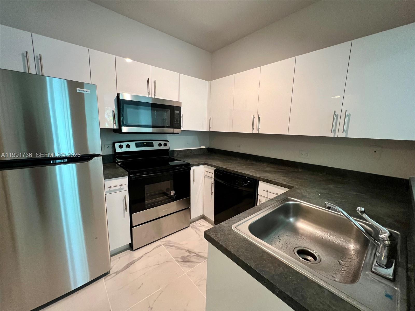 9172 Collins Avenue, Unit 214 Surfside, FL 33154 - Photo 5 of 33 a kitchen with stainless steel appliances granite countertop a refrigerator and a stove top oven