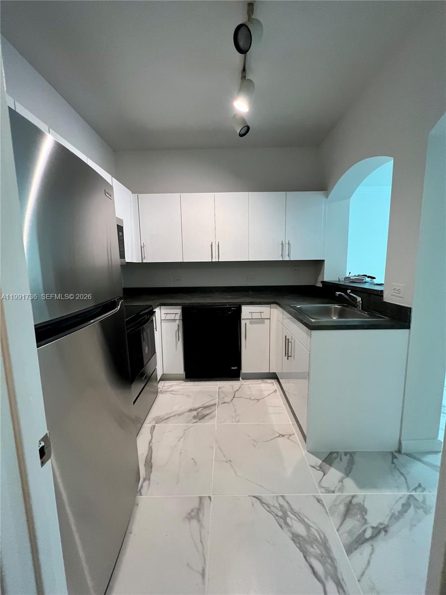 9172 Collins Avenue, Unit 214 Surfside, FL 33154 - Photo 6 of 33 a kitchen with a sink and cabinets