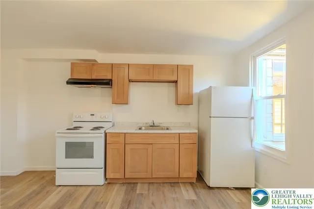 a kitchen with a sink a stove a refrigerator and a window