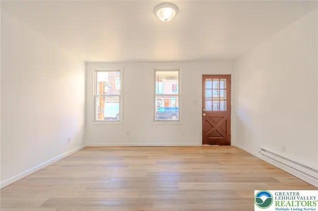 an empty room with wooden floor and windows