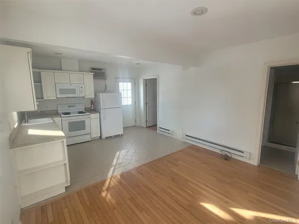 a view of a kitchen with white cabinets and wooden floor