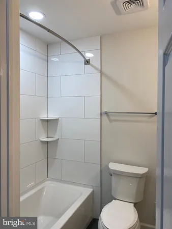 a white toilet sitting next to a bath tub