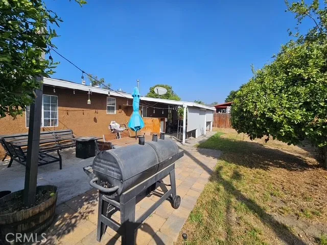 a view of a patio with table and chairs under an umbrella with large trees