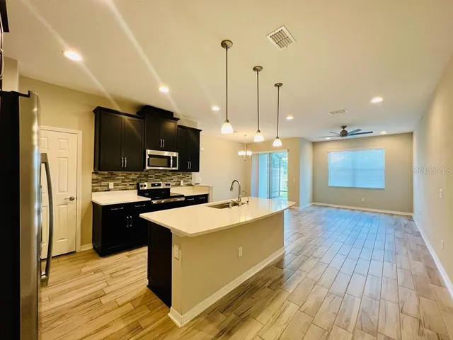 a large kitchen with stainless steel appliances kitchen island a large counter top and wooden floors