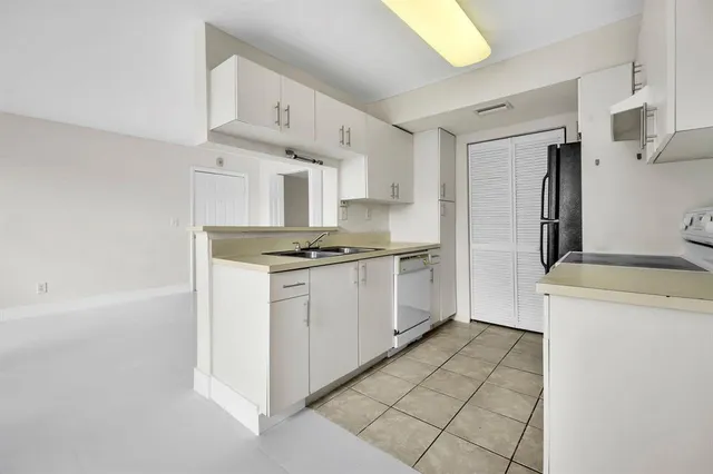 a kitchen with a refrigerator a stove top oven and cabinets