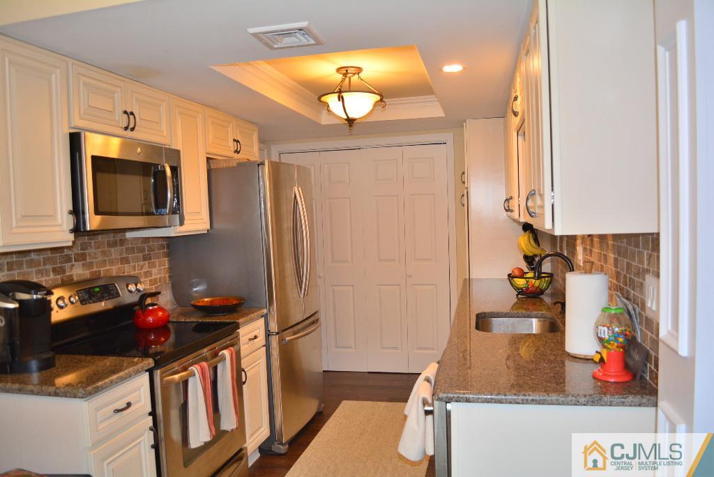 39 B Haddon Road Monroe Township, NJ 08831 - Photo 5 of 22 a kitchen with stainless steel appliances granite countertop a sink dishwasher stove and microwave with wooden floor