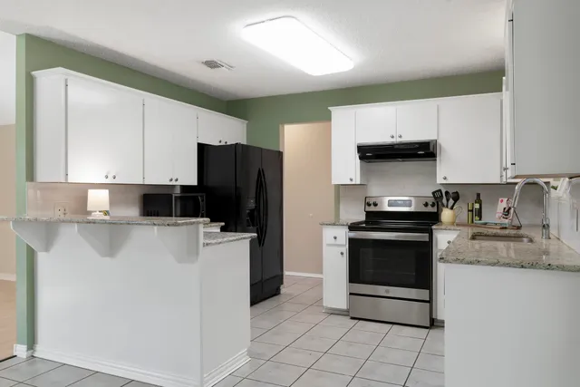 a kitchen with granite countertop a stove sink and refrigerator