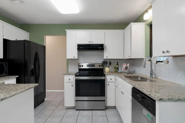 a kitchen with white cabinets and appliances
