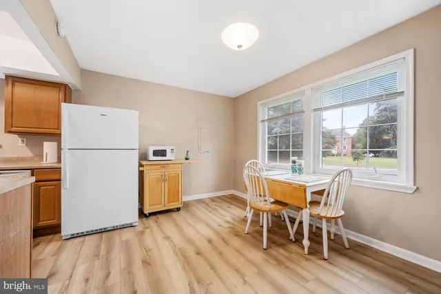 a dining room with furniture a kitchen wooden floor and a window