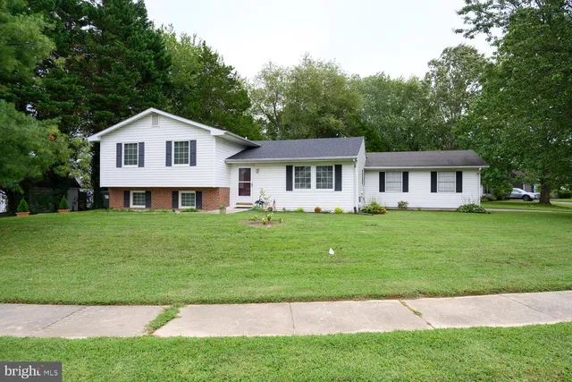a front view of a house with a garden and trees