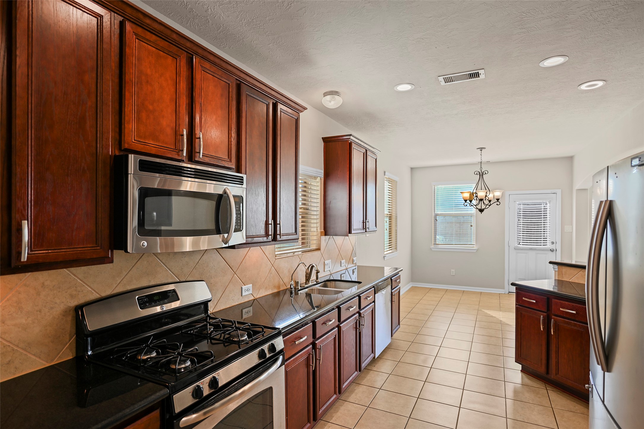8323 Rudy Brook Way Spring, TX 77379 - Photo 10 of 35 a kitchen with sink refrigerator and stove
