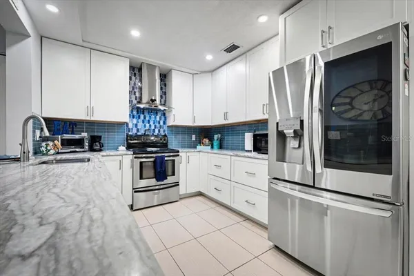 a kitchen with granite countertop a refrigerator and a stove top oven