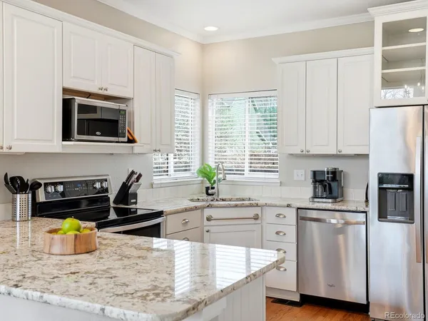 a kitchen with stainless steel appliances granite countertop a stove a sink a white cabinets a dining table and chairs