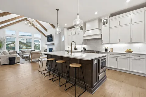 a kitchen with stainless steel appliances granite countertop a sink a stove a refrigerator and island with wooden floor