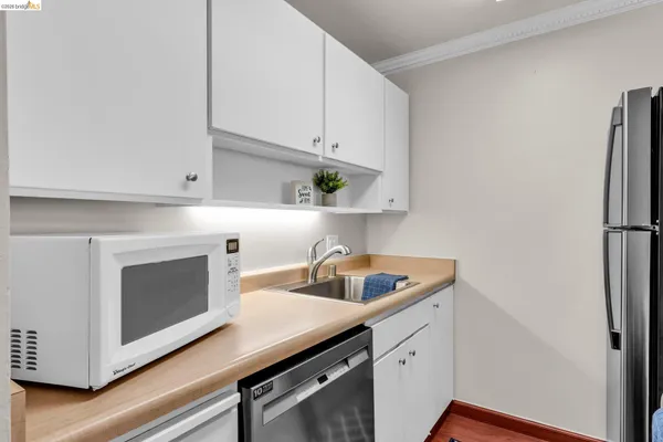 a kitchen with cabinets stainless steel appliances a sink and wooden floor