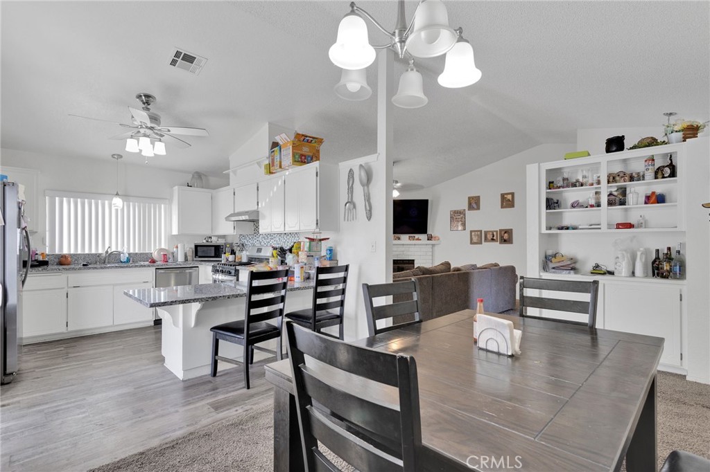 22517 Ojai Road Apple Valley, CA 92308 - Photo 12 of 25 a kitchen with stainless steel appliances kitchen island granite countertop a stove a sink a dining table and chairs with wooden floor