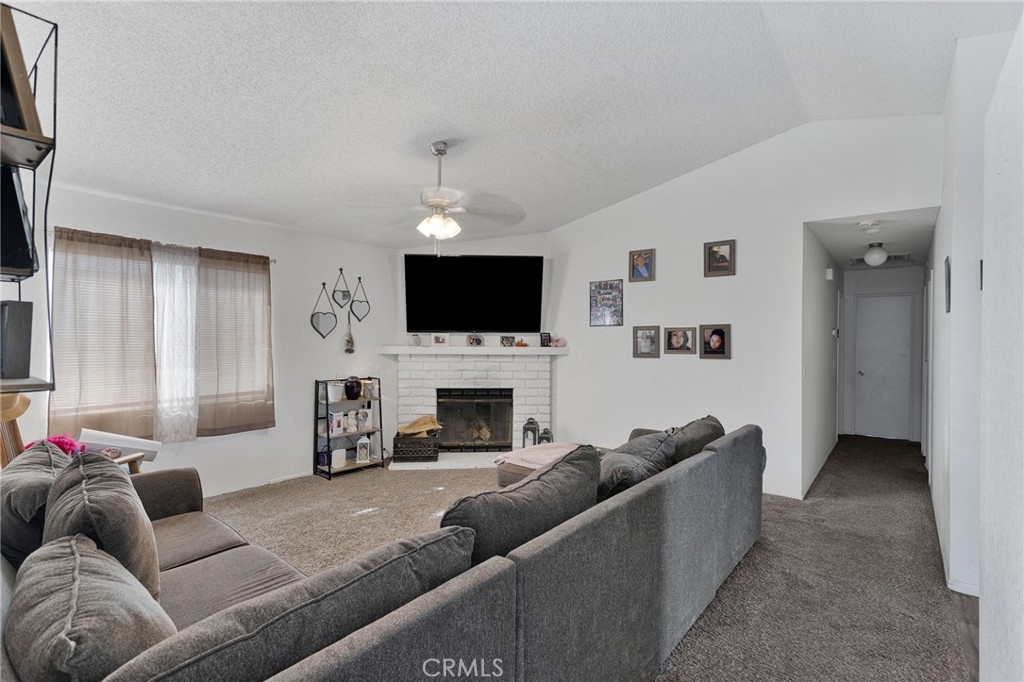 22517 Ojai Road Apple Valley, CA 92308 - Photo 8 of 25 a living room with furniture a fireplace and a flat screen tv
