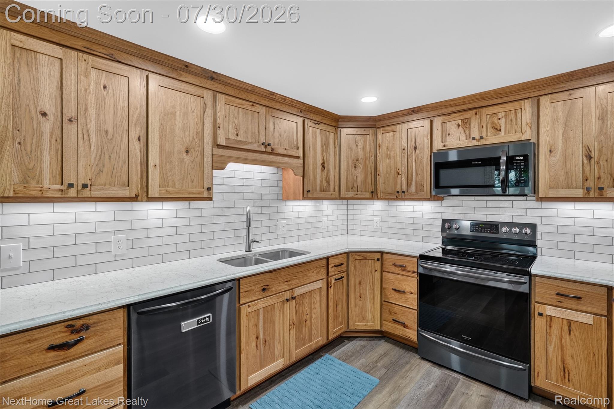 6249 North New Lothrop Road New Lothrop, MI 48460 - Photo 11 of 50 Kitchen featuring wood cabinetry, white subway tile backsplash, light-toned countertops, a double basin sink, and stainless steel appliances including a range, microwave, and dishwasher