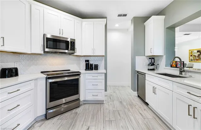 a kitchen with white cabinets stainless steel appliances and sink