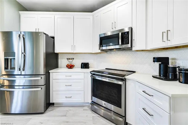 a kitchen with stainless steel appliances white cabinets and a stove a refrigerator with wooden floor