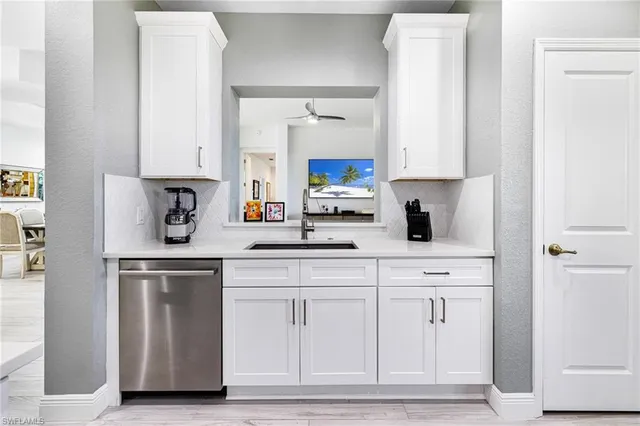 a kitchen with white cabinets and sink