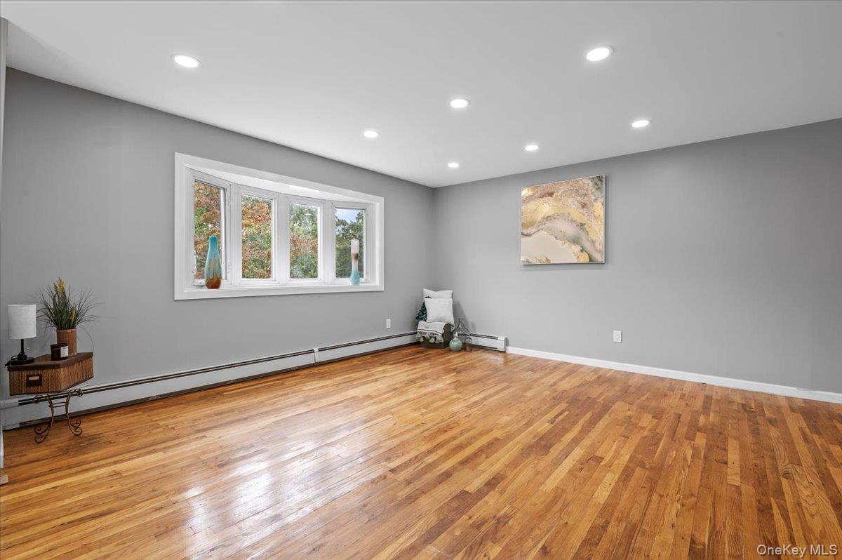 7 Bennett Court Copiague, NY 11726 - Photo 3 of 22 a view of an empty room with wooden floor and a window